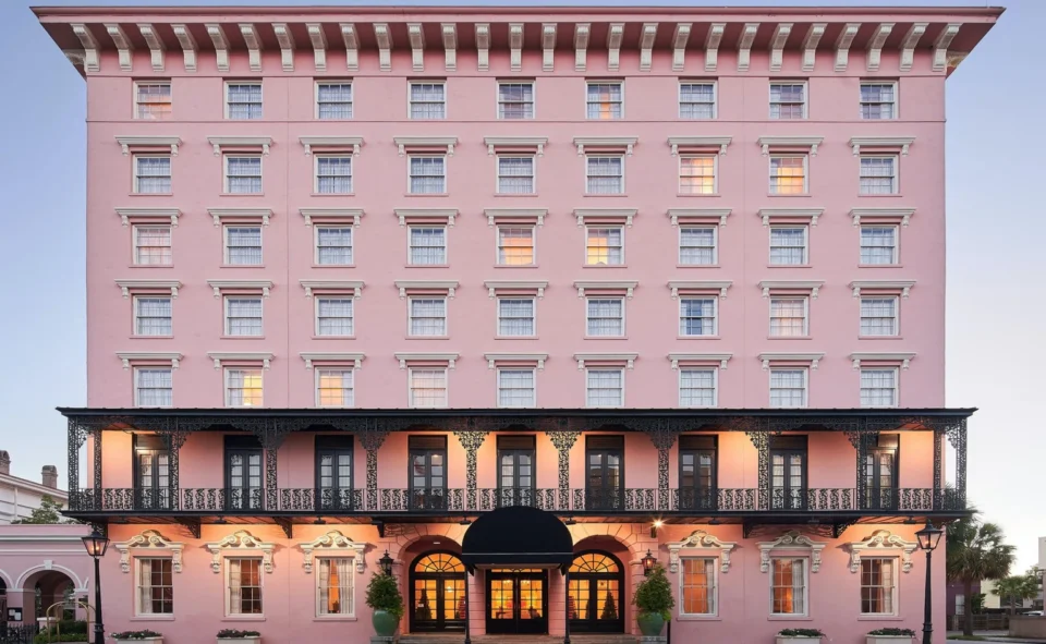 Pink historic hotel facade with white cornice trim, multiple stories of shuttered windows