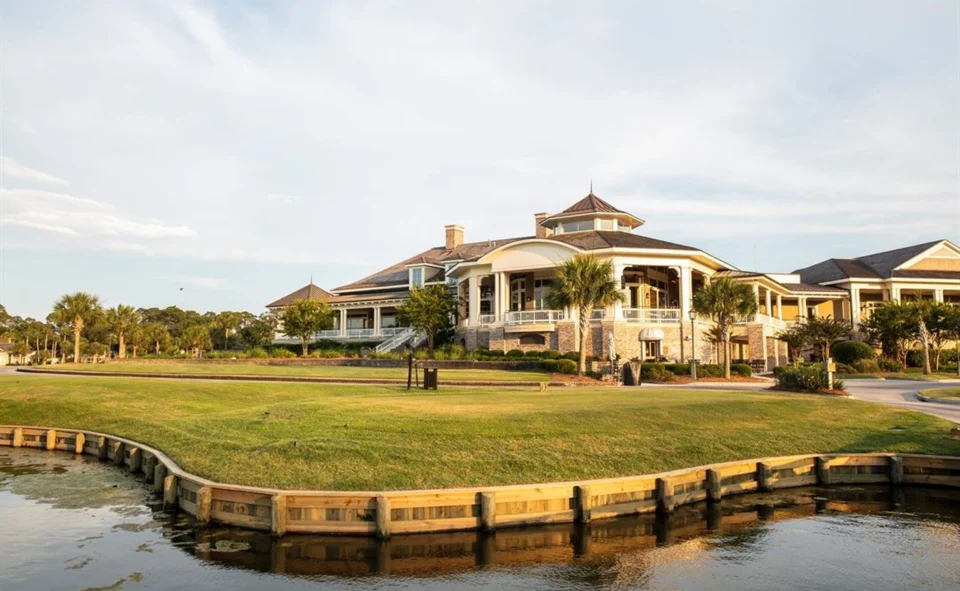 Waterfront resort clubhouse with a turreted roof and wraparound porches.