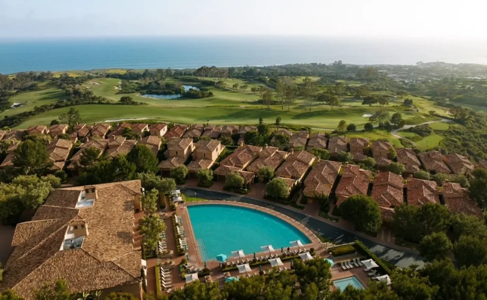 Aerial view of Pelican Hill Resort in Newport Beach with terracotta-roofed villas, a large curved pool
