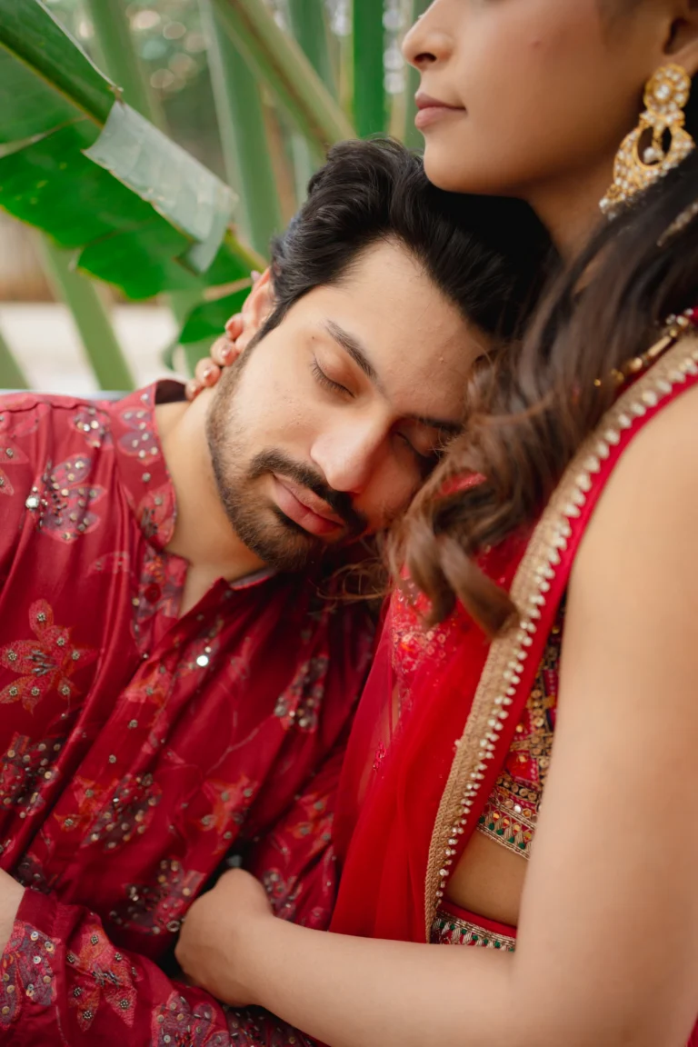 Lohith resting his head on his bride's shoulder, both in red.
