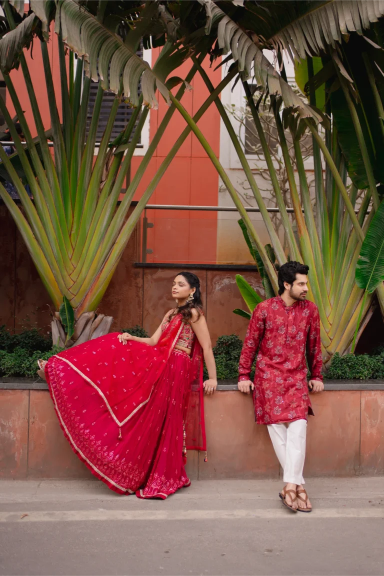Couple in matching red outfits beside a street ledge.