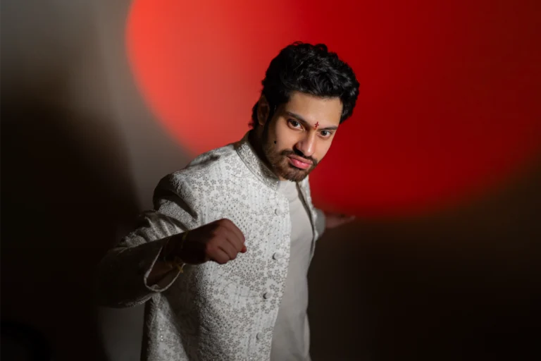 Lohith in a white sherwani playfully throwing a punch.