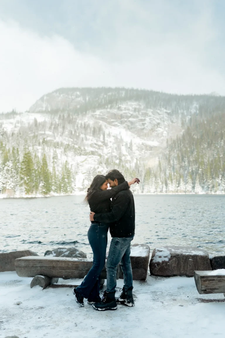 Couple holding each other at the edge of Dream Lake with snow.