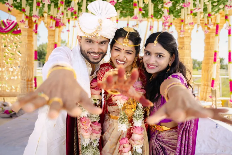 Couple and one of their friend showing their hands under the mandap.