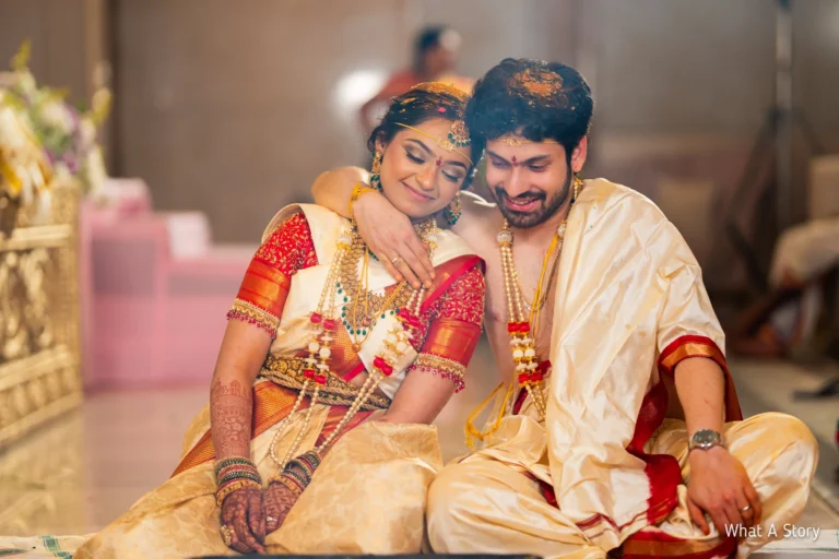 Srija and Lohith in cream and red silk seated together.