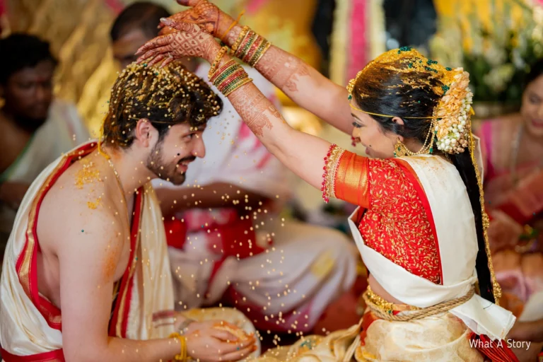 Bride sprinkling golden grains over the groom's head.